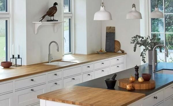 Helle Landhausküche mit Holzarbeitsplatten und weißen Fronten