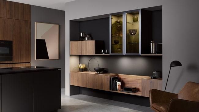 Holzfarbene Küche mit schwarzen Akzenten und passender Wohnwand