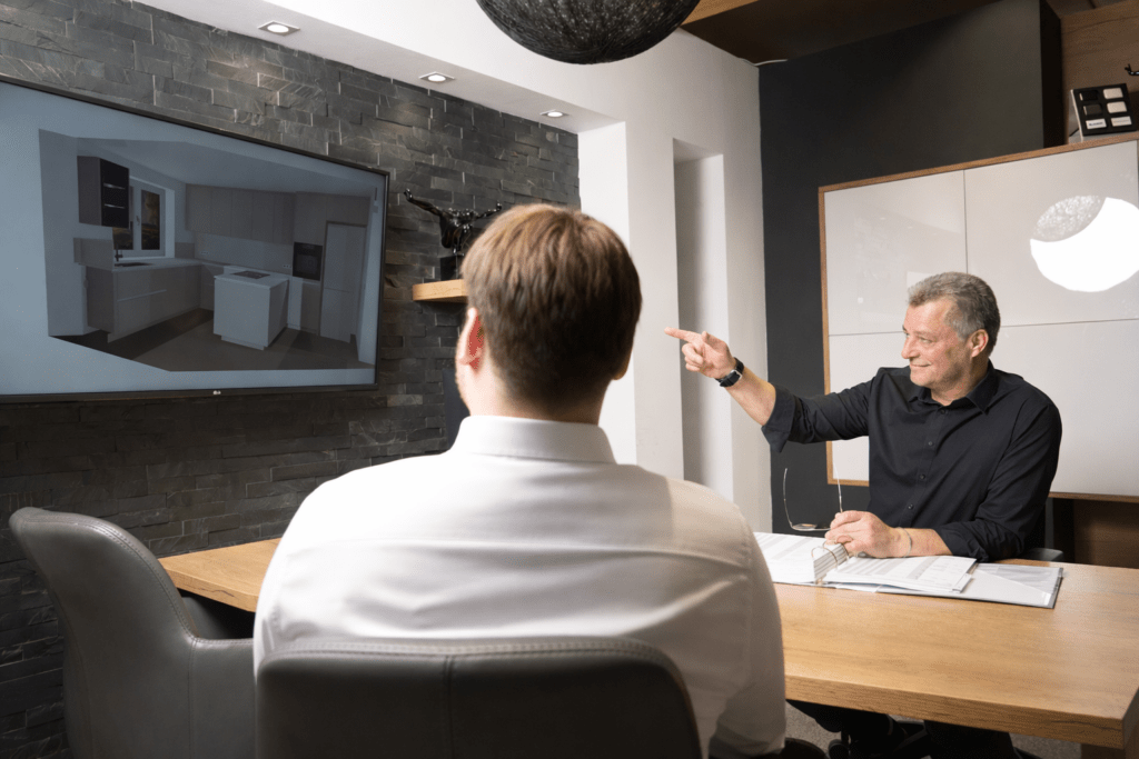 Beratungsgespräch bei küchen WALTHER: Küchenplaner zeigt dem Kunden die 3D-Planung am Bildschirm