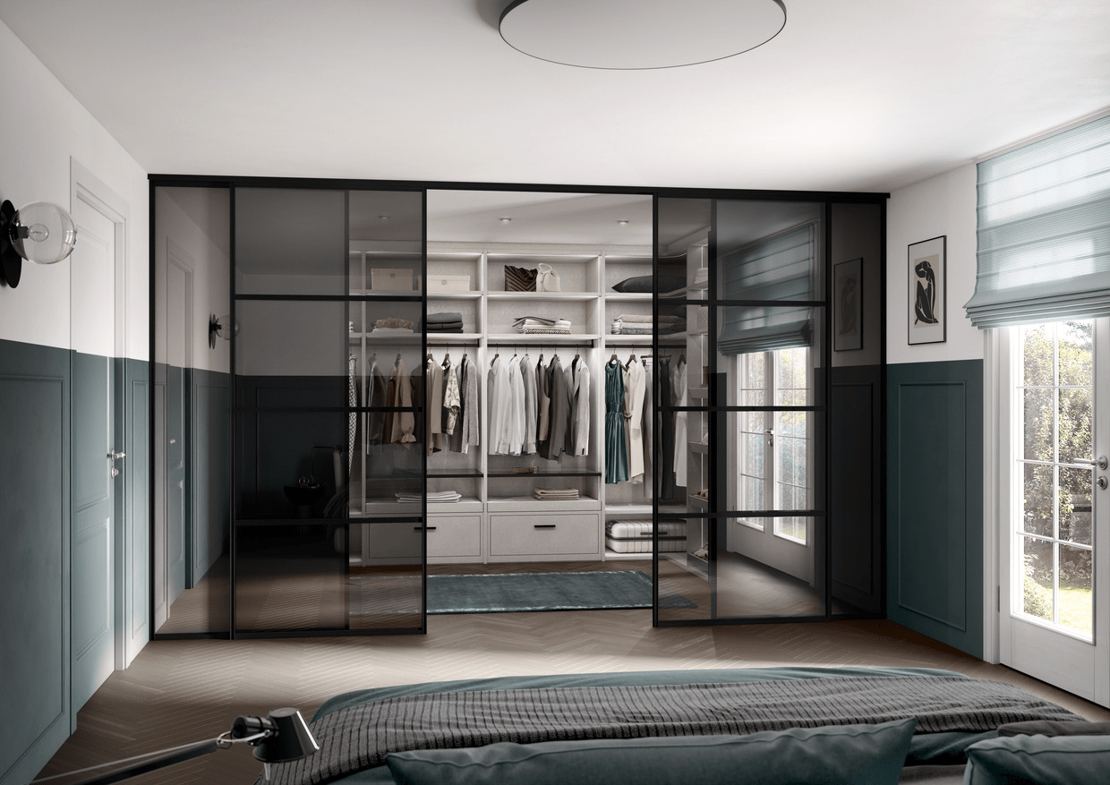 Detailansicht eines Gudcina Kleiderschranks in Weiß, beleuchtetes Regalsystem mit Kleiderstange, Schubladen und Glasfachböden hinter einer eleganten Glastür mit schwarzem Rahmen.