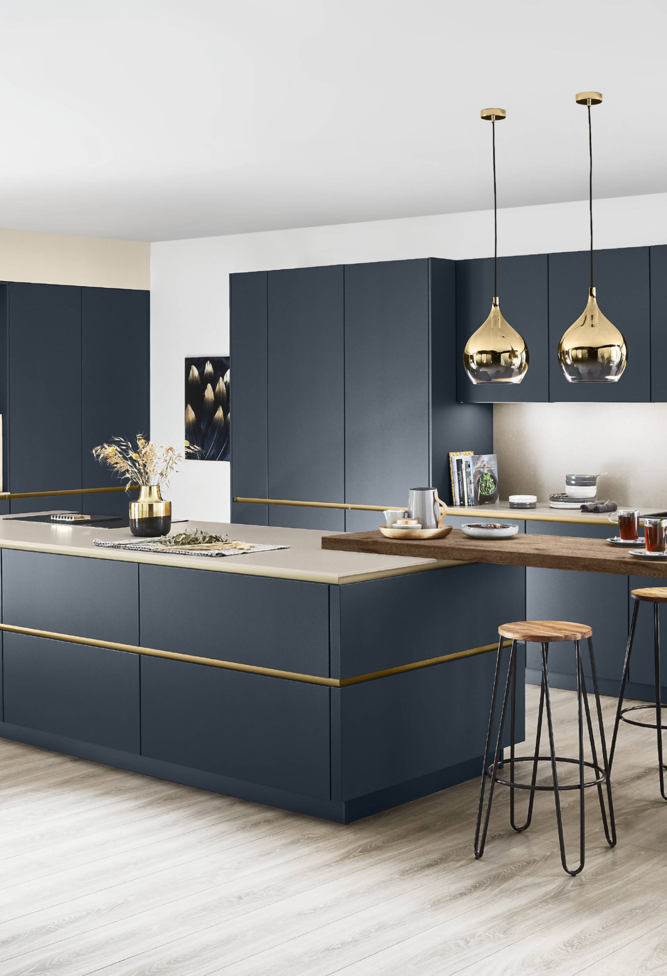 Nobilia Designerküche in tiefem Petrolblau-Matt mit umlaufenden Goldprofil-Griffleisten, heller Steinarbeitsplatte und angebautem Holztresen mit Barhockern – elegante Küche mit zwei goldenen Glas-Pendelleuchten und hellem Eichenparkett