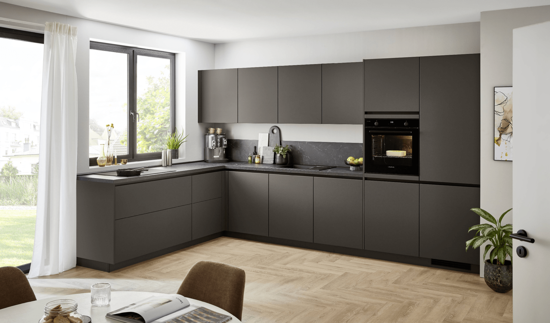 Moderne L-Küche von Nobilia in Anthrazit mit grifflosen Fronten, dunkler Arbeitsplatte in Steinoptik und integriertem Backofen in einer hellen Wohnung mit Fischgrätparkett