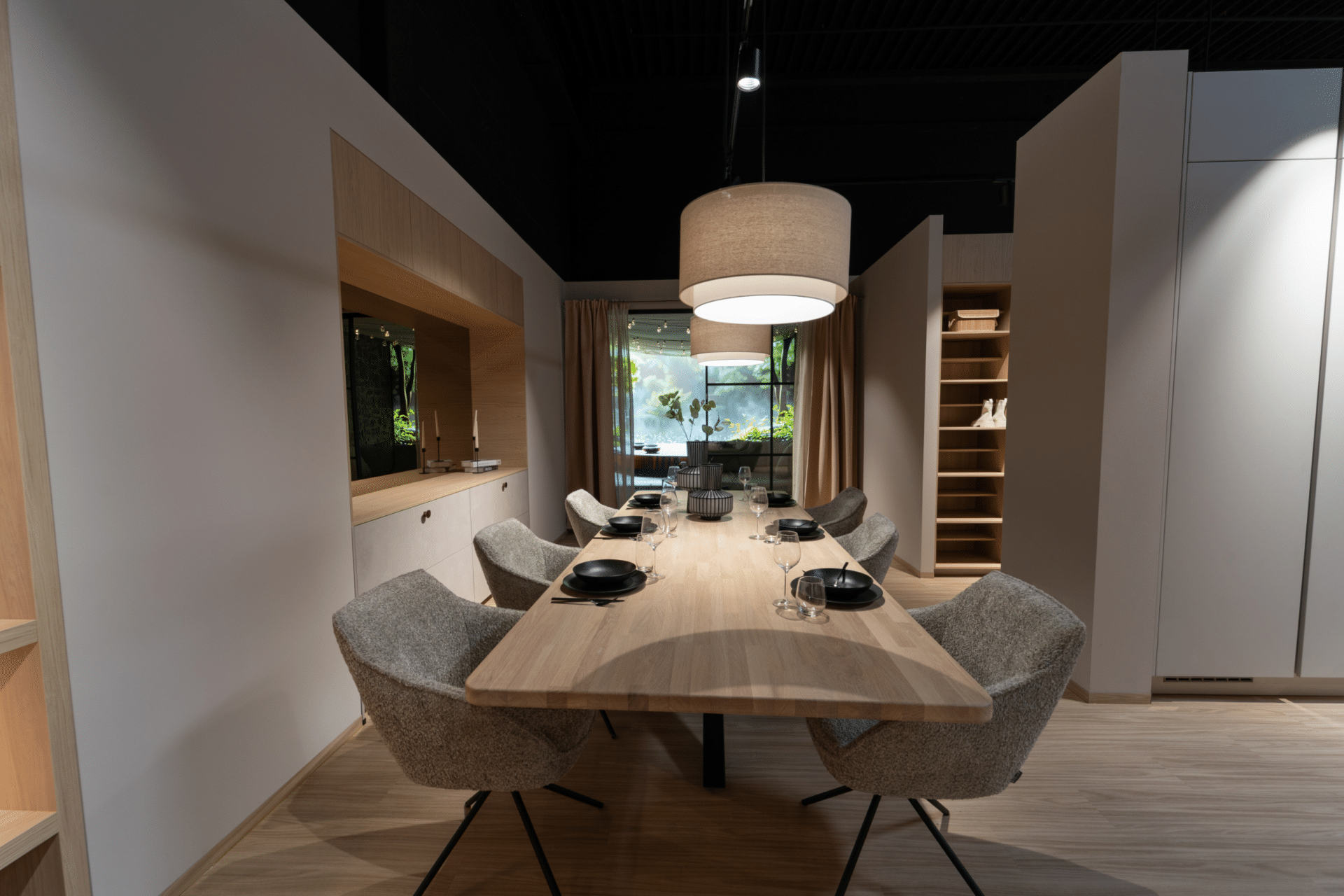 Essbereich in der Ausstellung im Küchenstudio Viernheim mit Holztisch, Polsterstühlen und Pendelleuchte
